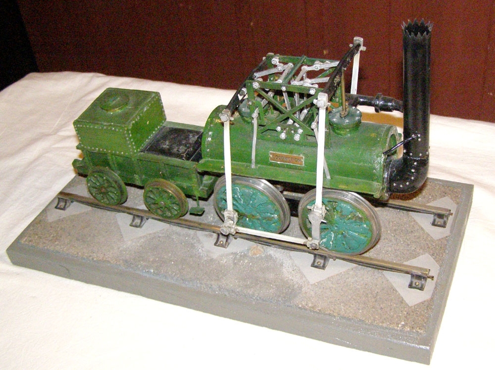 Modell av ångloket Locomotion i skala 1:20.
Stockton-Darlington Railway-
Tillverkad av plåt och järn. Grönmålad, med svartmålad skorsten. Vevstakar av
grå metall.