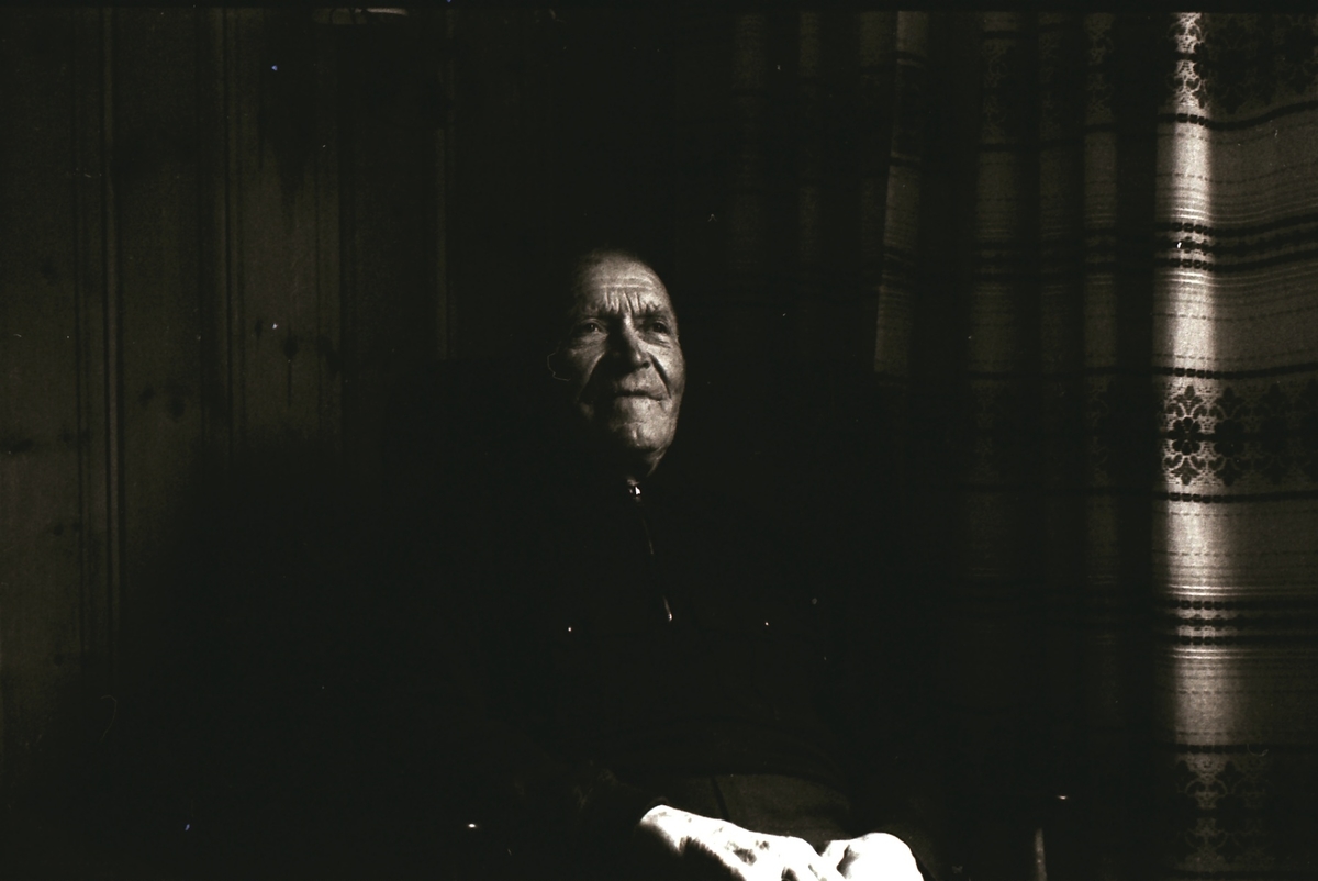 Portrettfotografi av Tore Knivsflå inne ved et stuevindu.