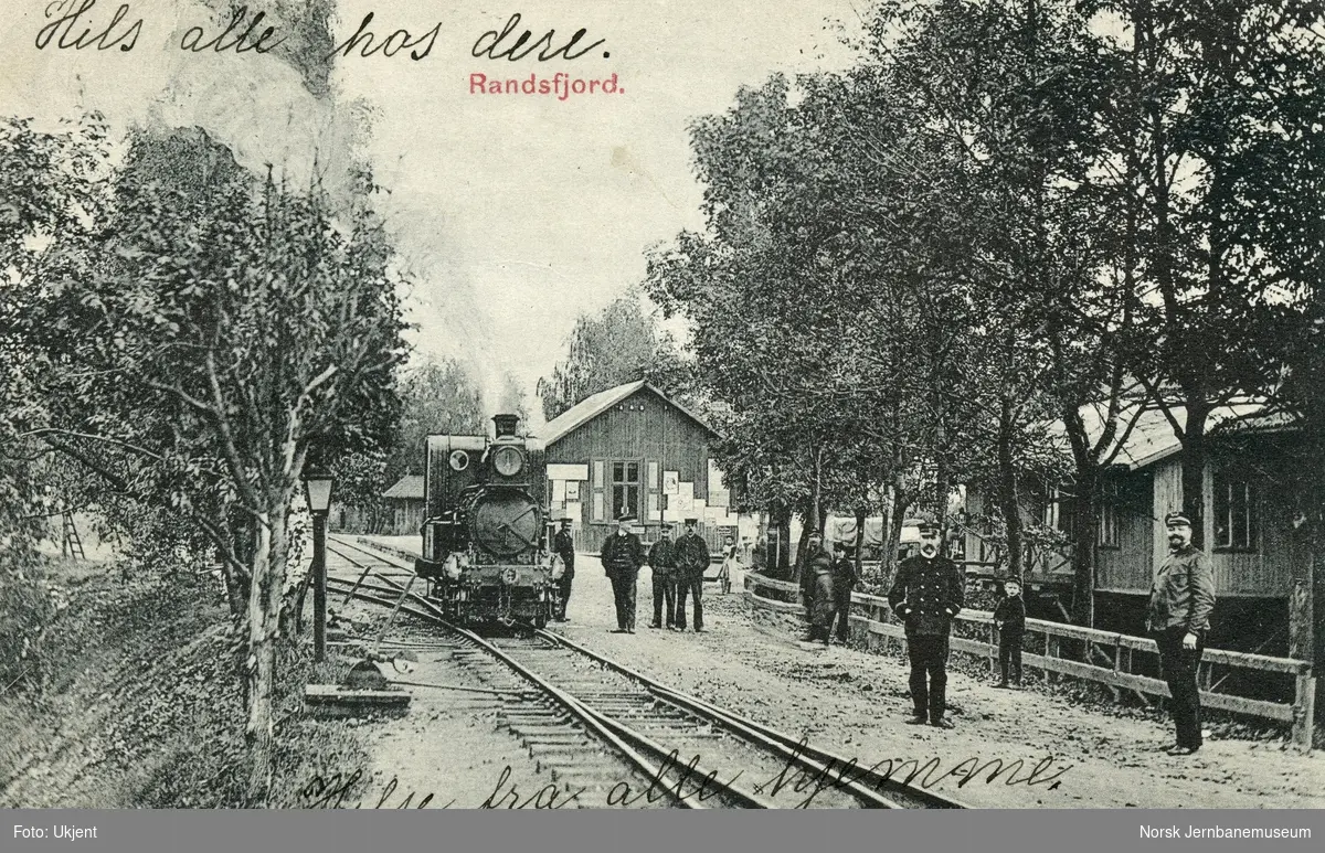 Smalsporet damplokomotiv, trolig type IV, og personale på Randsfjord stasjon
