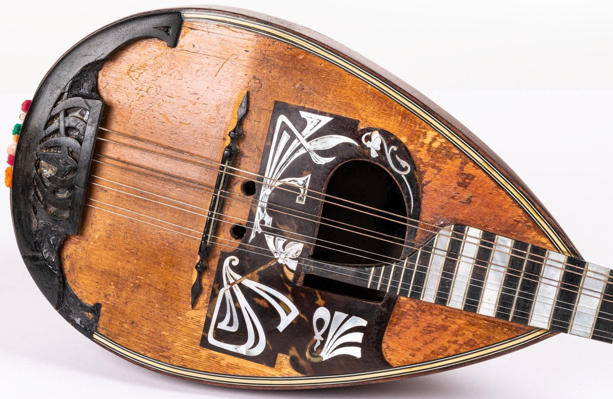 Mandolin. Något nött och trasig. I botten av mandolinen finns en bild av förutvarande ägaren La Bella Ingeborg, cirkusartist från gävle.
Till mandolinen finns ett brunt fodral av brunt bomullstyg.