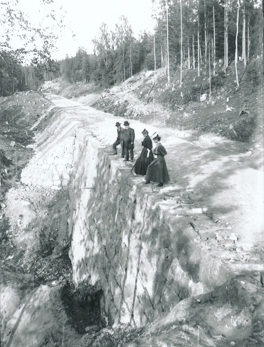 Bestyrer Wilhelm og Nicoline Rydgren sammen en annen mann og kvinne står på jernbane- eller veitrasé under anlegging.