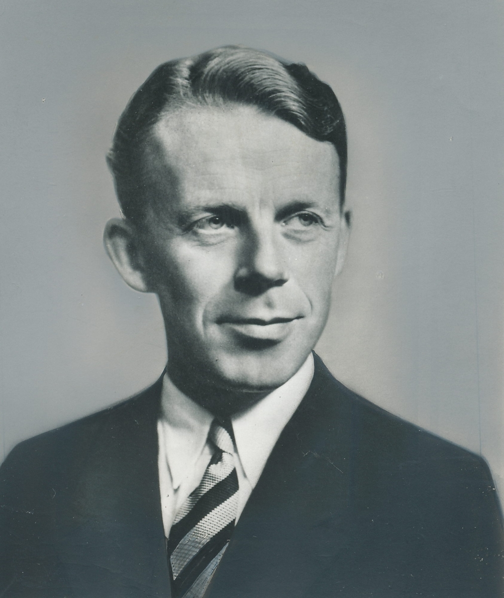 Portrett av mann i 50-årsalderen, iført dressjakke, skjorte og stripete slips.