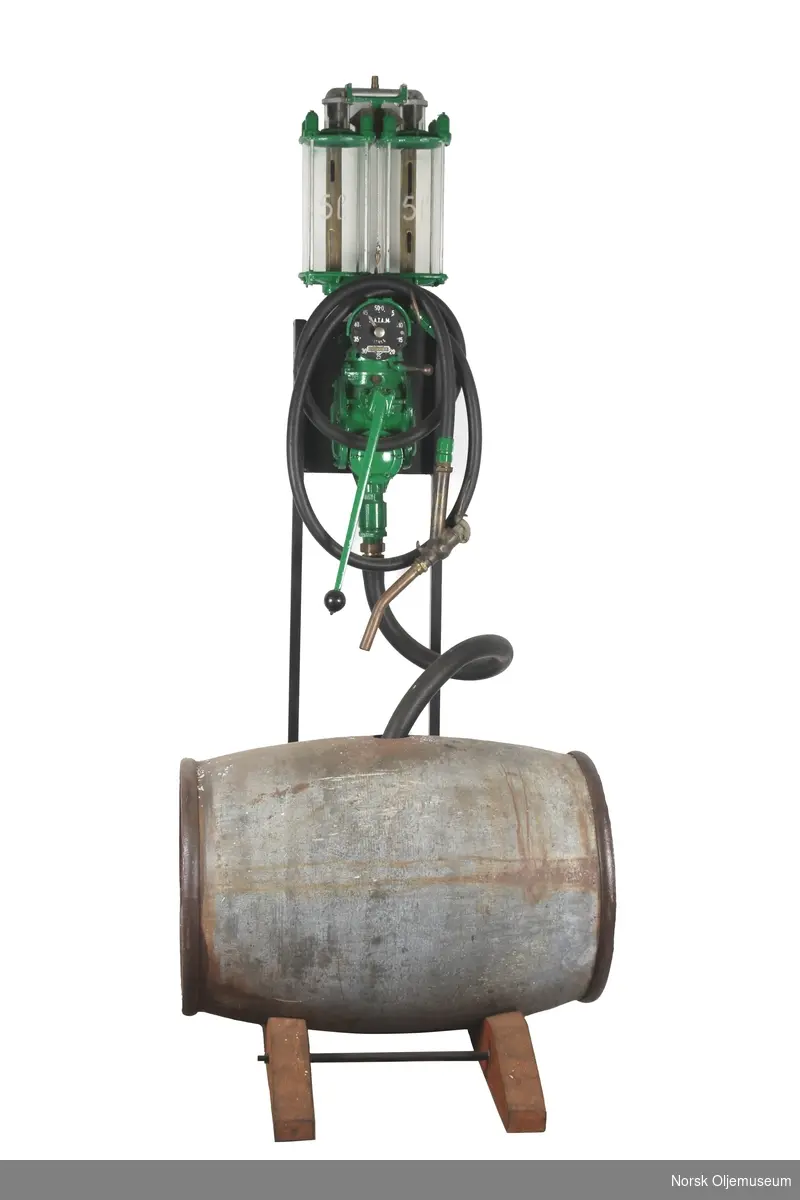 Bensinpumpe bestående av et oljefat, en bensinkanne og et stativ med to 5 liters bensintanker av glass og tallskive.