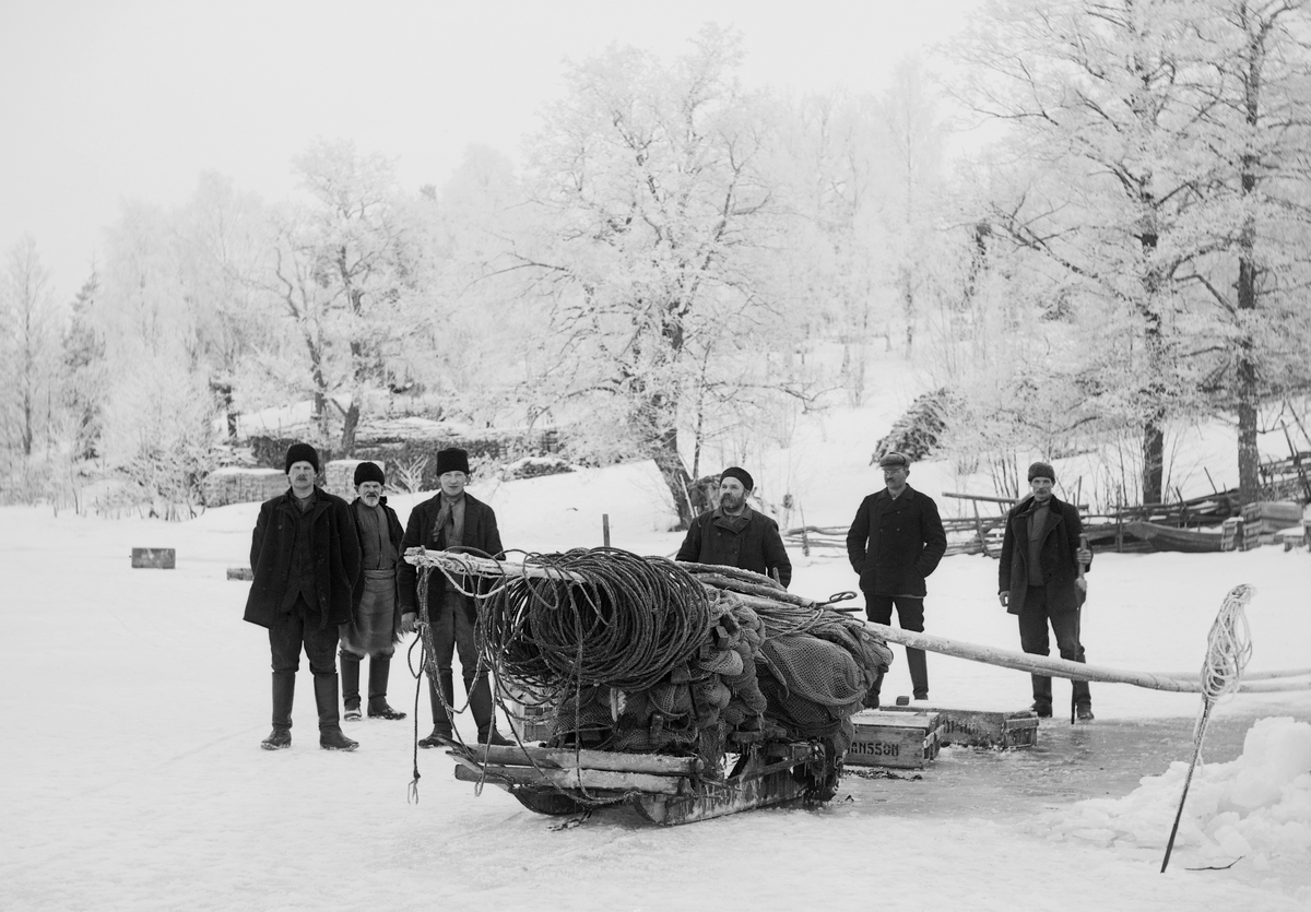 Notdragning av strömming på Gropviken i Sankt Anna. Fotografen har förevigat fiskelaget på isen invid torpet Storskogen under Ramsdal. Året är 1914.