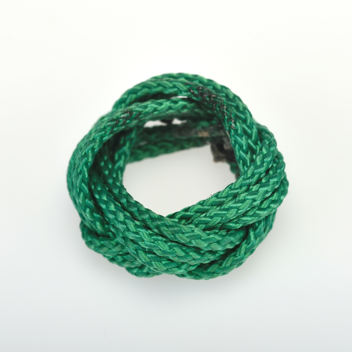 En skjerfknute/speiderknute flettet av grønn bomullssnor. Denne typen knute ble brukt av guttespeidere i alderen 11-16 år (speidere i tropp) frem til 1978. Denne er trolig hjemmelaget.