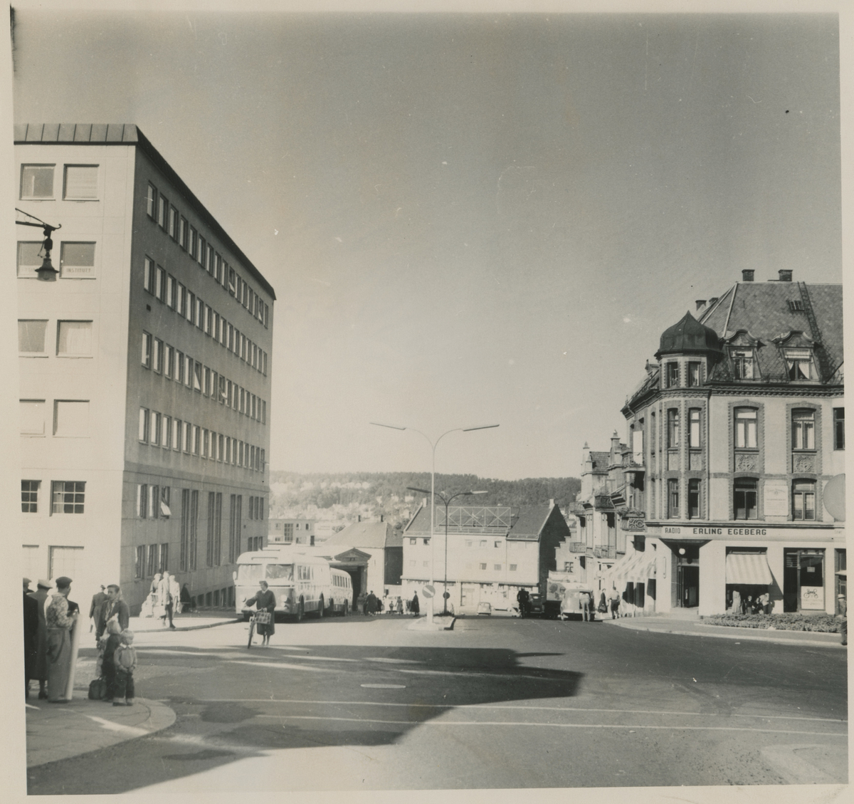 Torggata. Ca. 1960. 

Fotograf har stått i Torggata.
Detaljer:	Dronningens gate 1 til venstre, bybussen og høyvekta, Gudes gate 4. Torvgården til høyre.
Historikk: Dronningens gate 1 ble oppført i 1956. Høyvekta ble revet i 1962.