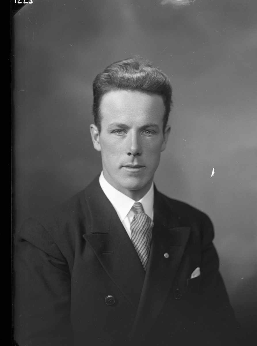 Porträtt av Gustaf Lilja, en ung man i kostym, ljus skjorta och snedrandig slips. Näsduk i bröstfickan.