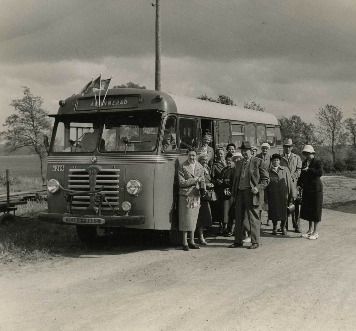 "De gamlas utfärd", Kållered RK, 1950-tal. En abonnerad buss med tre vimplar står parkerad utefter en landsväg. Bredvid står några personer som ska åka med på en rundtur. På fotot ses bland annat Rut Bengtsson (Långåker), Olga Holmen (Vommedal), Ottilia Pettersson (Livered) samt Ester Nyberg (Lugnet).