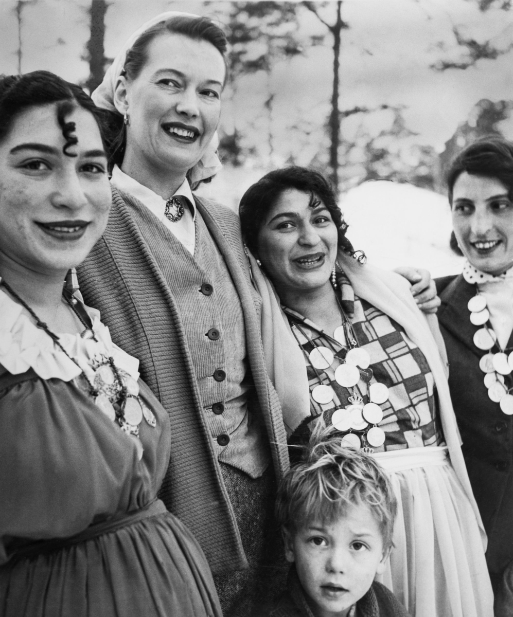 En grupp romska kvinnor ler mot kameran. Tre av kvinnorna bär mynt i kedjor runt halsen.