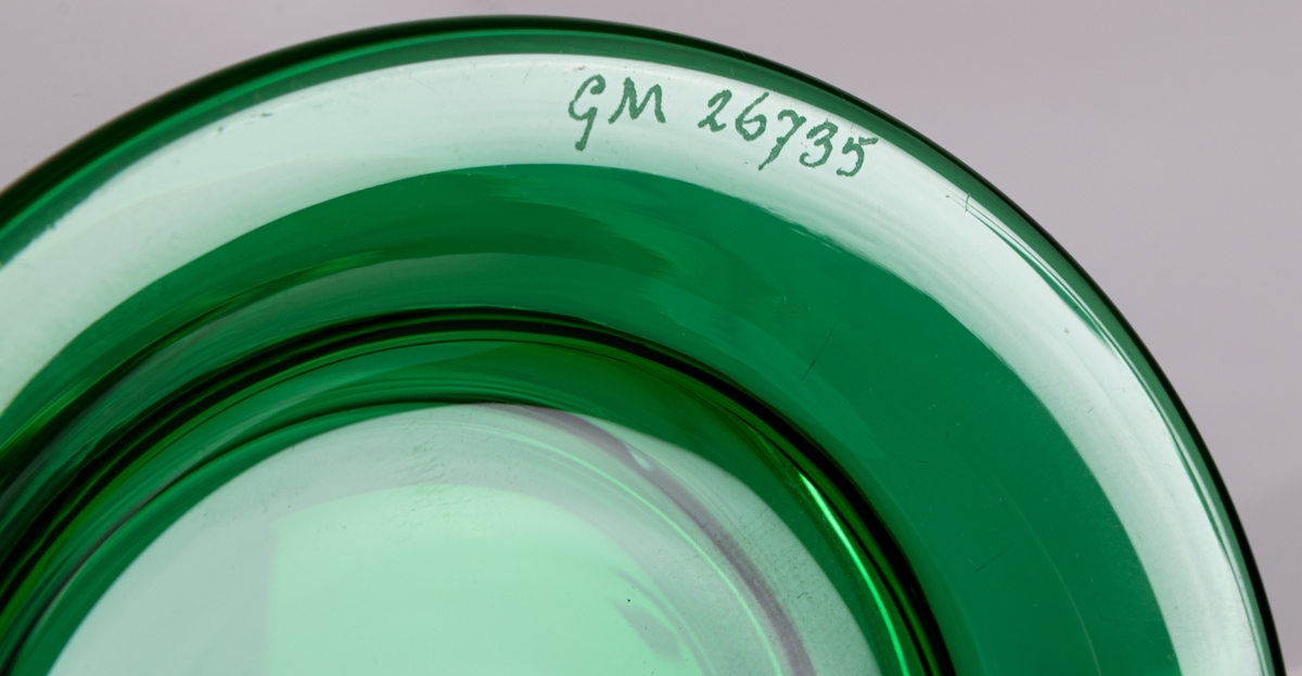 Skål. Raka, utåtlutande sidor i ofärgat glas på låg, utkragad fot i grönt glas. Design Gunnar Cyrén för Orrefors Glasbruk.