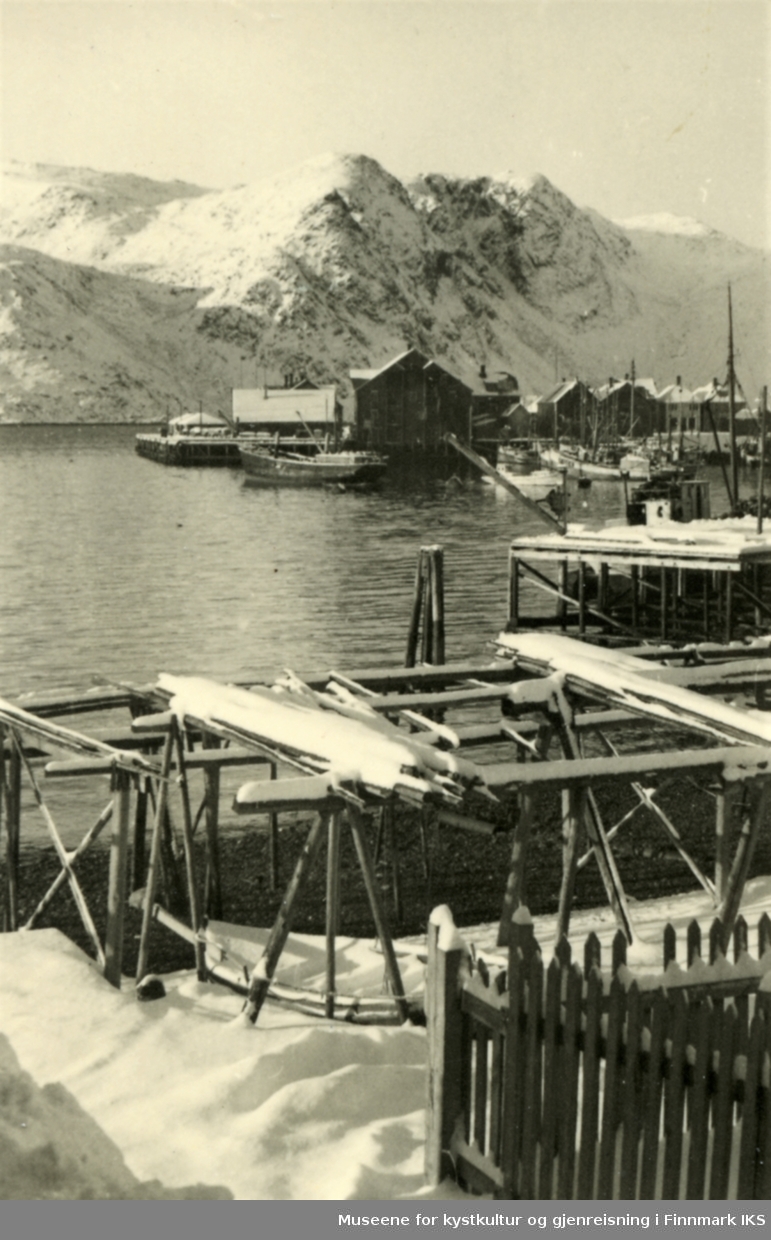 Honningsvåg. Bildet tatt fra Vågen. Dampskipskaia med bebyggelse i bakgrunnen. Fiskehjeller i forgrunnen. 1942.