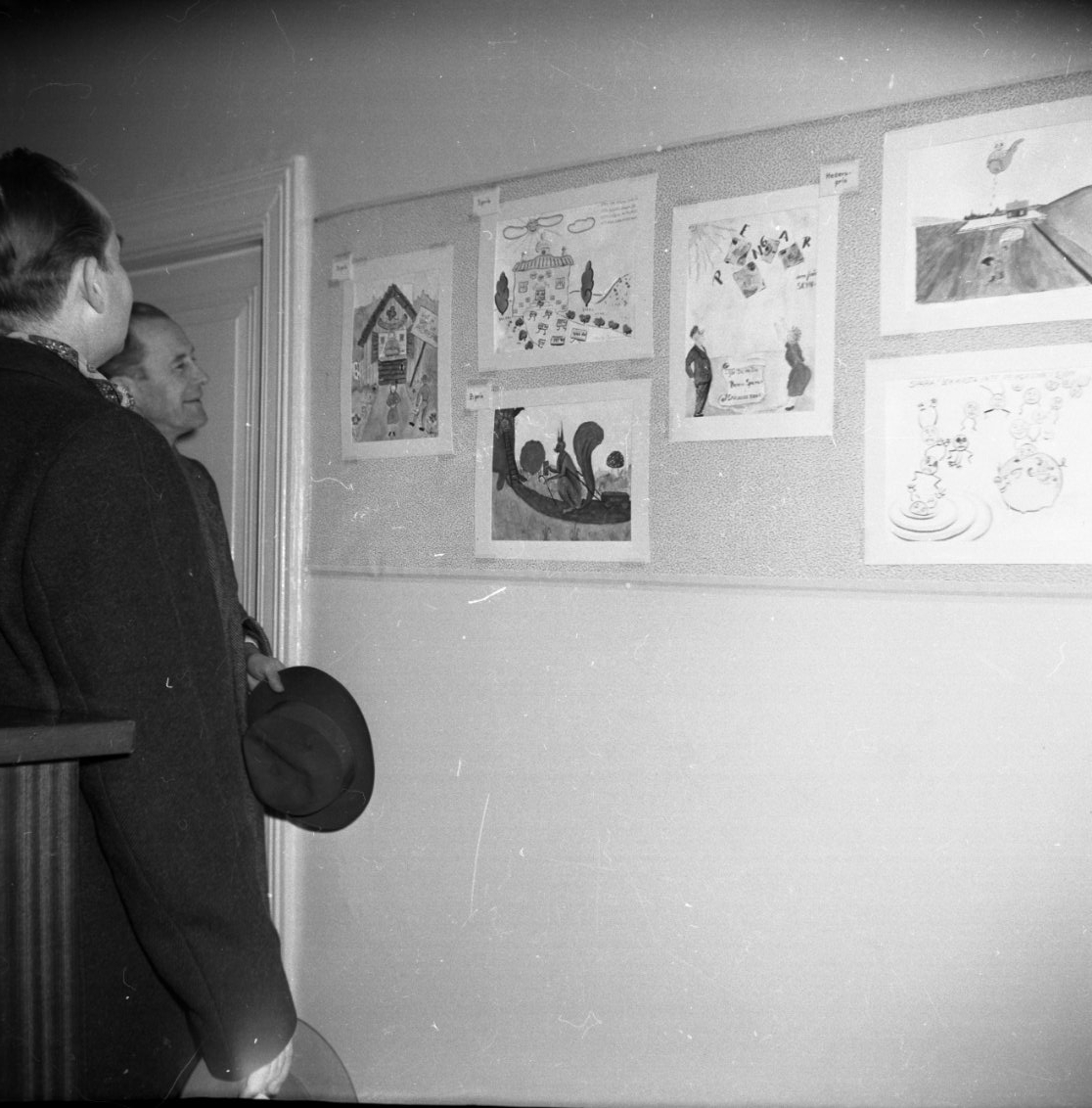 Två män tittar på en tavla med teckningar inne på Smålands Bank.
