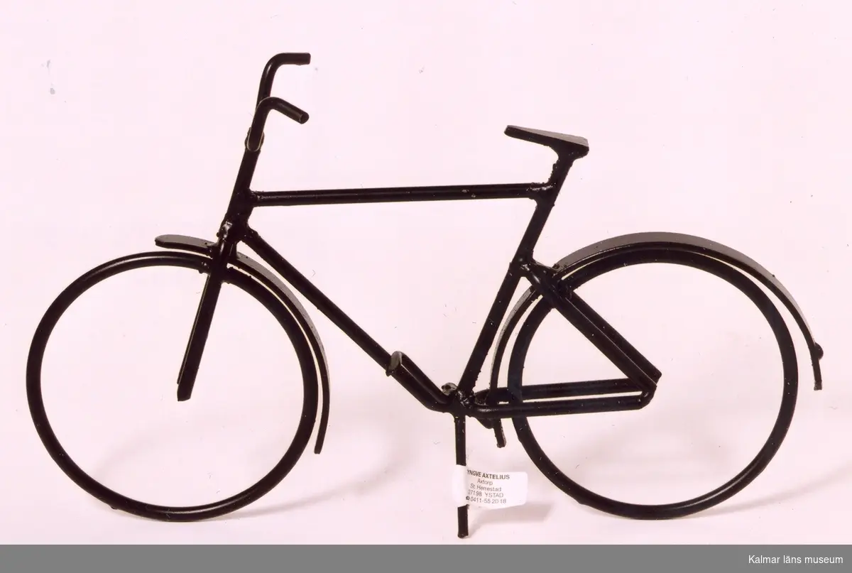 KLM 39586:45 Cykel av metalltråd, svartmålad. Tillverkad i konstsmide, svetsad. Herrcykel med vanligt styre. Prydnadsföremål. Tillverkad av Yngve Axtelius som var verksam som trådslöjdare.