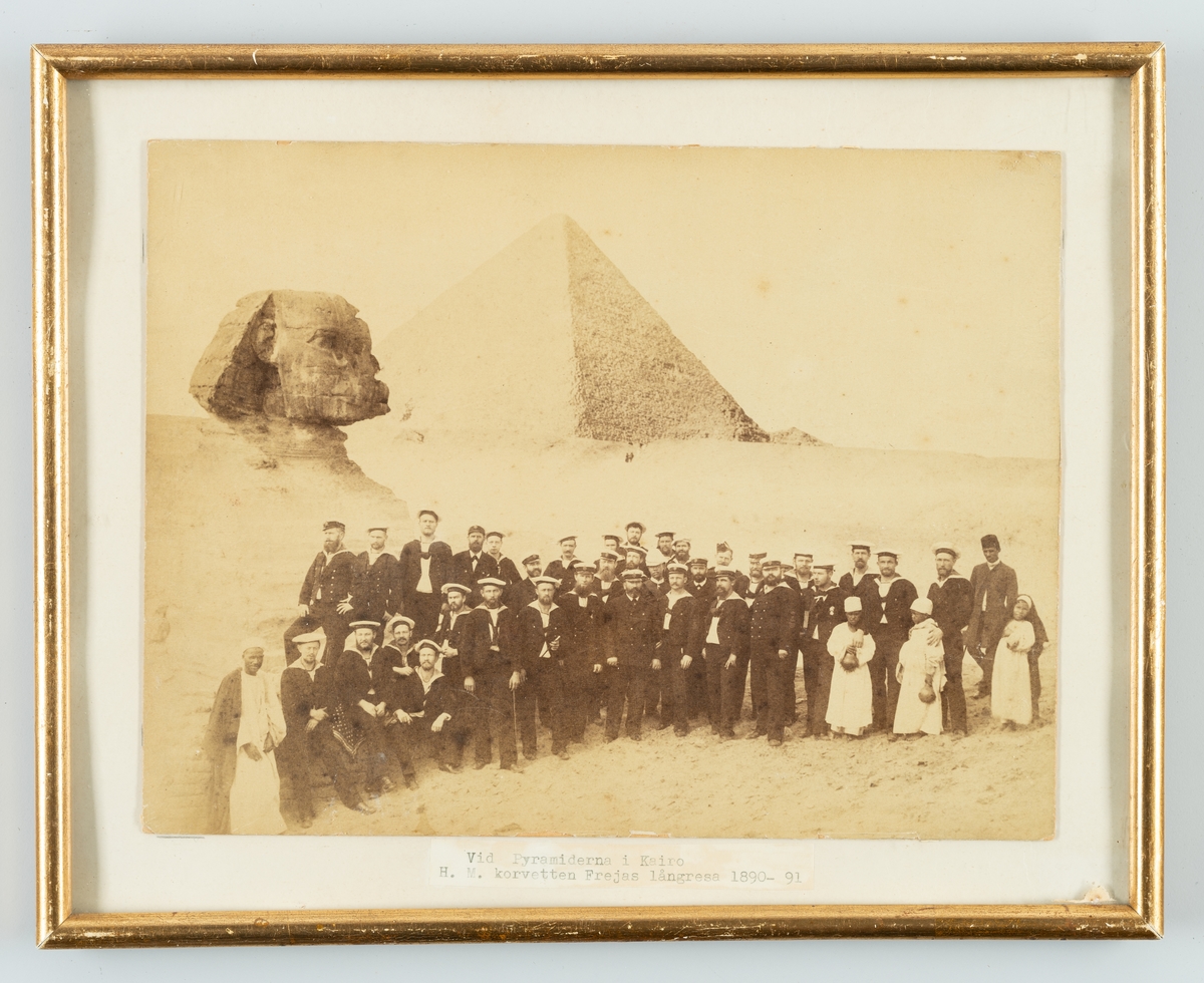 Bilden föreställer korvetten FREJAS besättning som har tagit uppställning framför sfinxen och pyramiderna för en gruppfoto under långresan 1889-90.