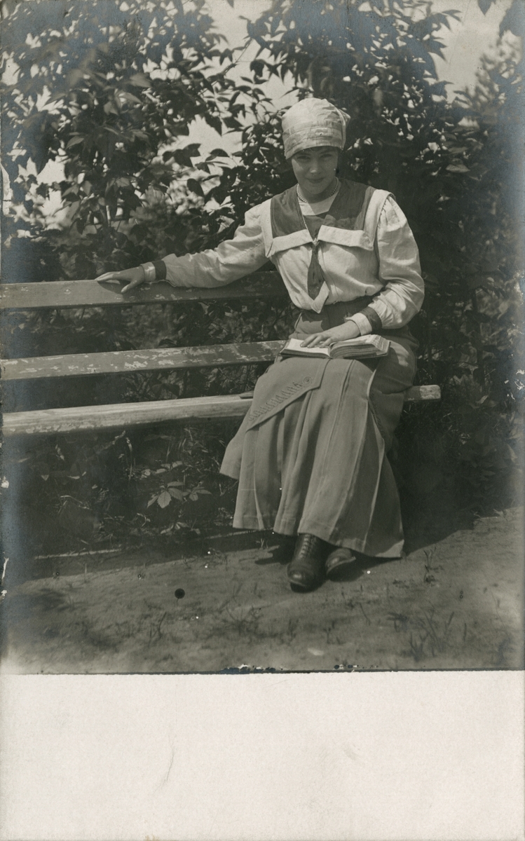 Bildet viser Victoria Rostin (senere gift Bachke) på en benk. Sannsynligvis mellom 15-16 år, før 1914.