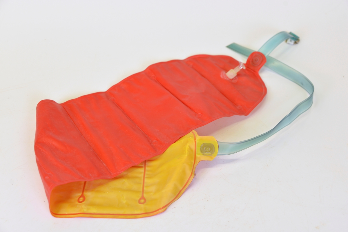 
Uppblåsbar simdyna med band med spänne. Röd ovansida, gul insida.