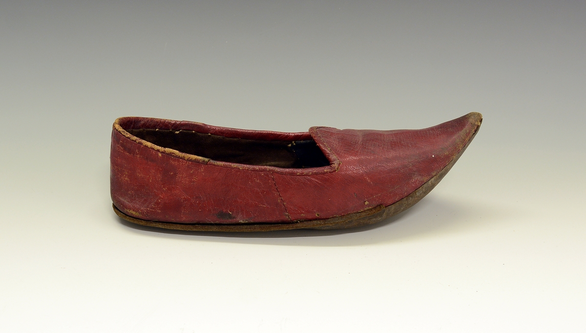 Spissnutet sko. Fra protokollen: Rød egyptisk tøffel av saffiansskind, med lersaale. Spidssnutet. (R. Berge)