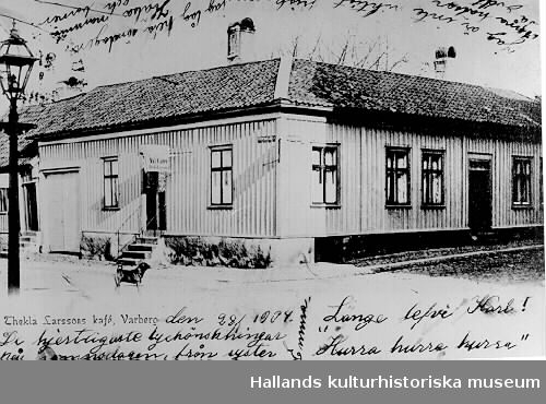 Brevkort, "Thekla Larssons kafé, Varberg.", sänt den 28/1 1904. Det låg i hörnet Västra Vallgatan-Norrgatan, kv Berget och på skylten står det "Nya Caféet, Thekla Larsson". Nedanför trappan står en hund och i förgrunden syns en gatlykta.

För fler uppgifter se tidningsartikeln "Hemma hos för 100 år sedan", publicerad i Hallands Nyheter 2000-04-20.