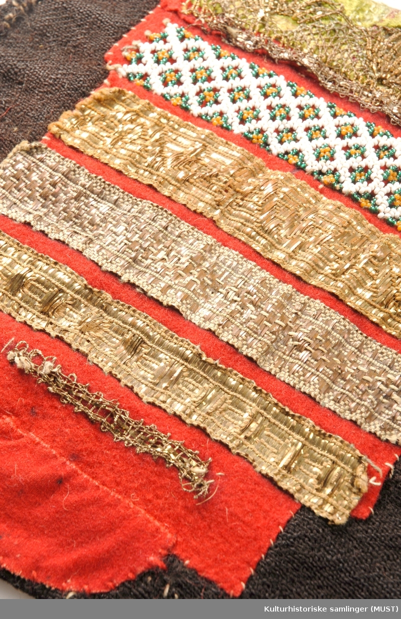 Rødt og grønt silkebånd med gjennombrutt gullbånd. Perlebord (hvit, grønn, brun), gullbord, sølvbord.