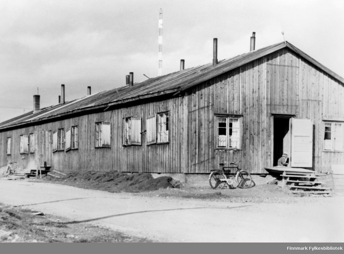 Bildet viser en boligbrakke i Vadsø fotografert en gang etter 1948. Ref. radiomastene som sto ferdige ca. 1948. 