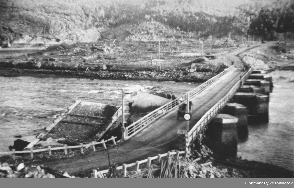 På bilde sees den brua som russerne bygde etter krigen ved Elvenes. Rester etter den gamle brua sees i vannet til venstre. Bildet er tatt i 1945.
