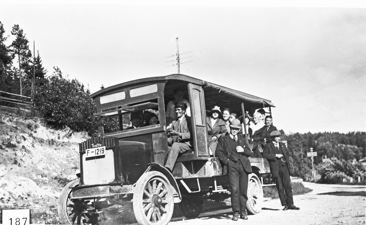 Pent kledde passasjer ved rutebilen «Trafikk» (bilmerket er Traffic). Det var den første bussen i Eggedal. Sjåfør Anstein Dokkeberg. Bilen blei kjøpt i 1920.