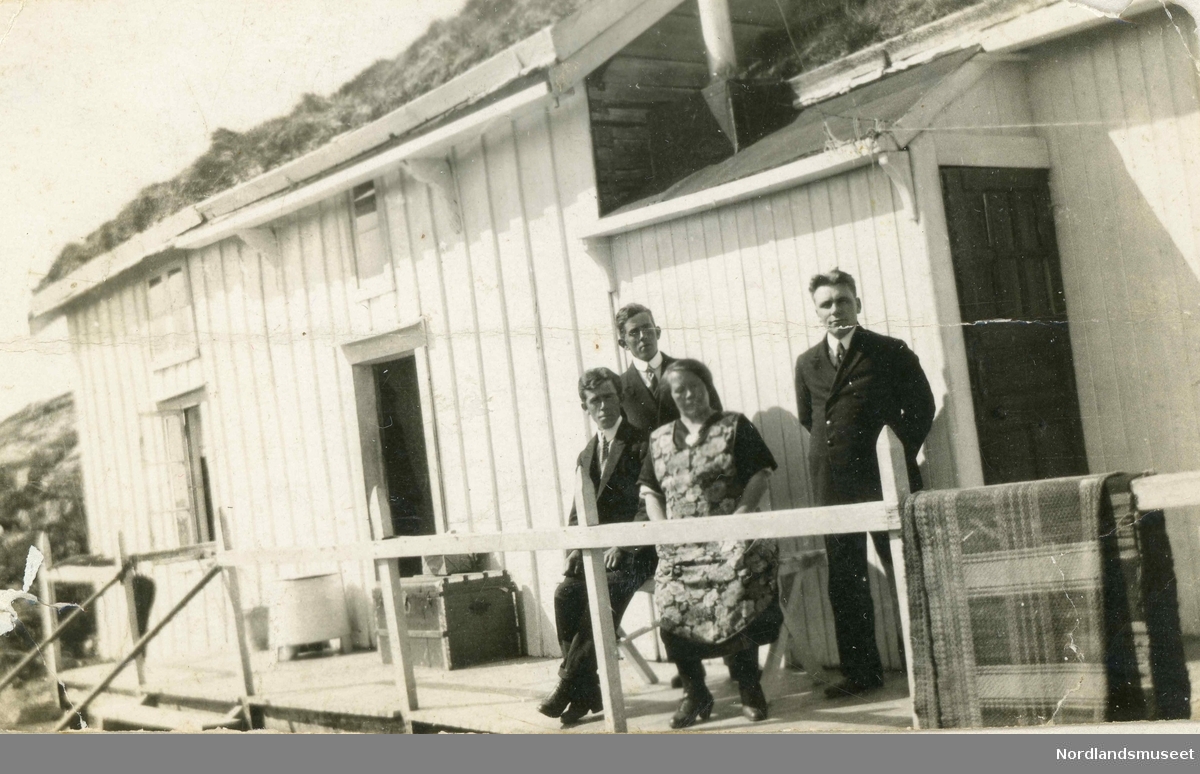 Hus på Gamøya i Engelvær med 3 menn og en dame. Mennene er tre brødre. Fra venstre: Torleif, Lothar og Sigfred Aasgaard. Kvinnen er Ellen Nielsen, tjenestejente som kom fra Holkestad.