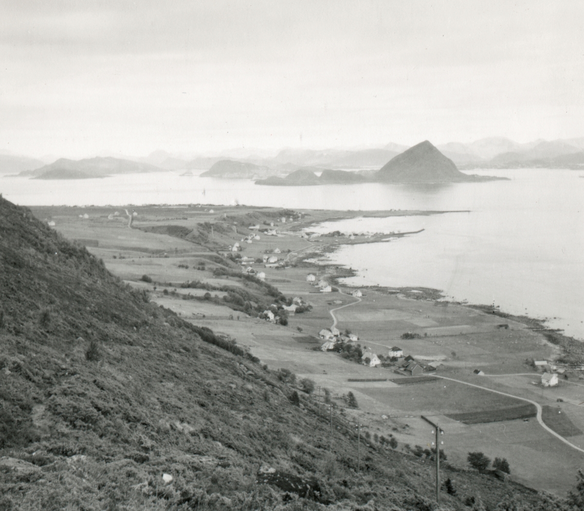 Oversiktsbilde fra sør-østsiden av Godøy der Gøygarden ligger. Fjellene med Sukkertoppen i bakgrunnen.
