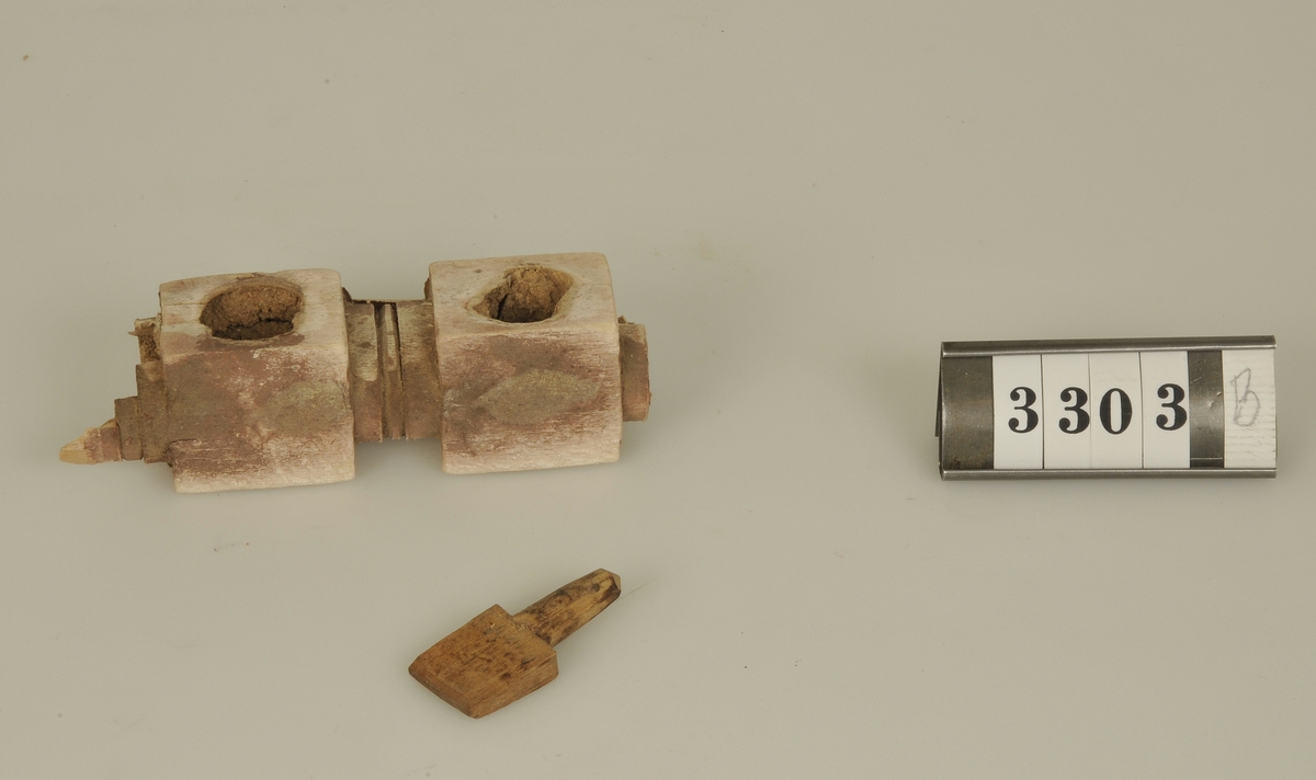 Enligt givarens påskrift kommer byggnadsdetaljerna från ett koptiskt tempel nära Kairo. Templets ålder över 1600 år. 
a) En tegelfärgad marmorbit från ett mosaikgolv. Storlek: 5,3 x 2,4 cm.
b) Del av ett skulpterat trägaller. Storlek: 10 x 3 cm.

Har tillhört de Adelsköldska samlingarna.