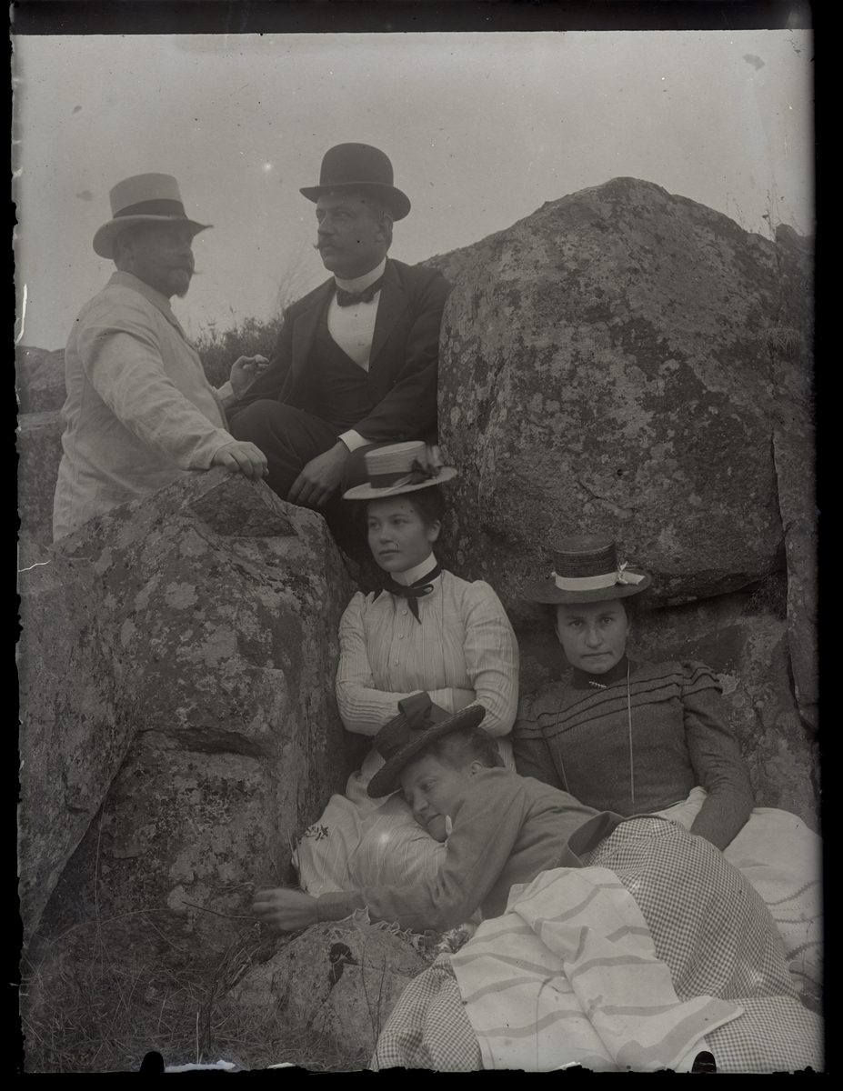 Tre kvinnor och två män poserar vid en sten, ca 1910.