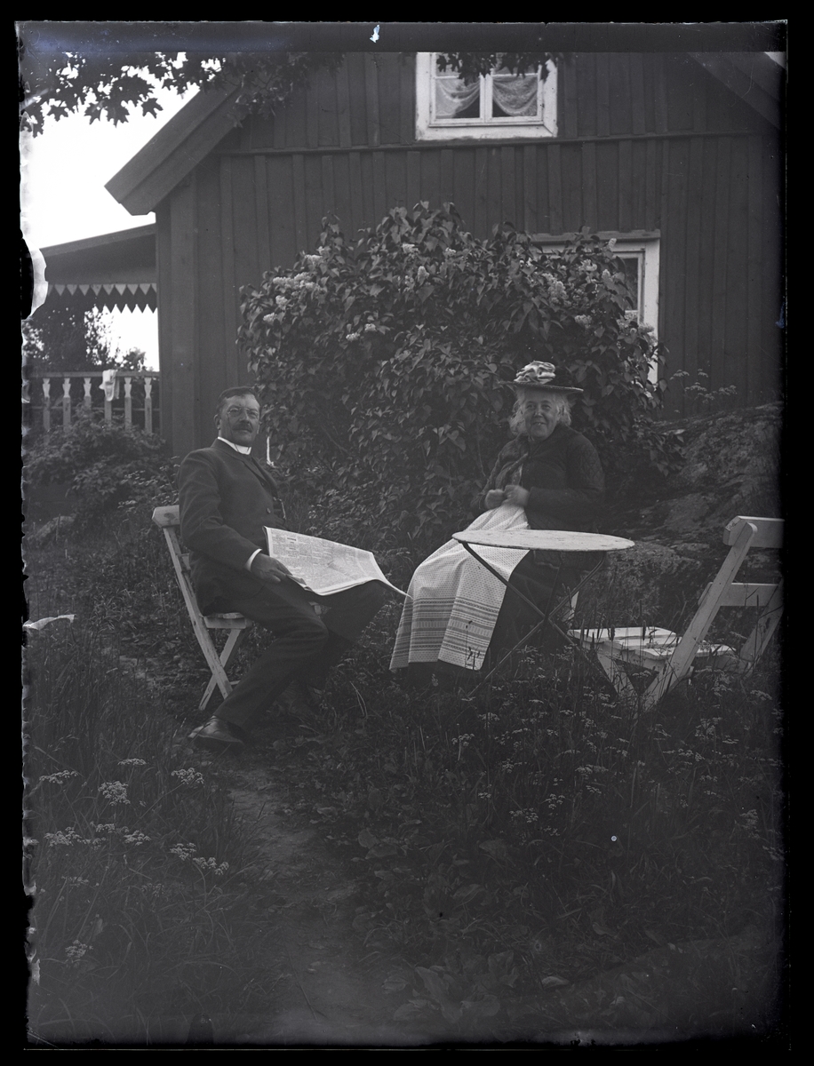 Äldre par sittande i en trädgård, ca 1910.