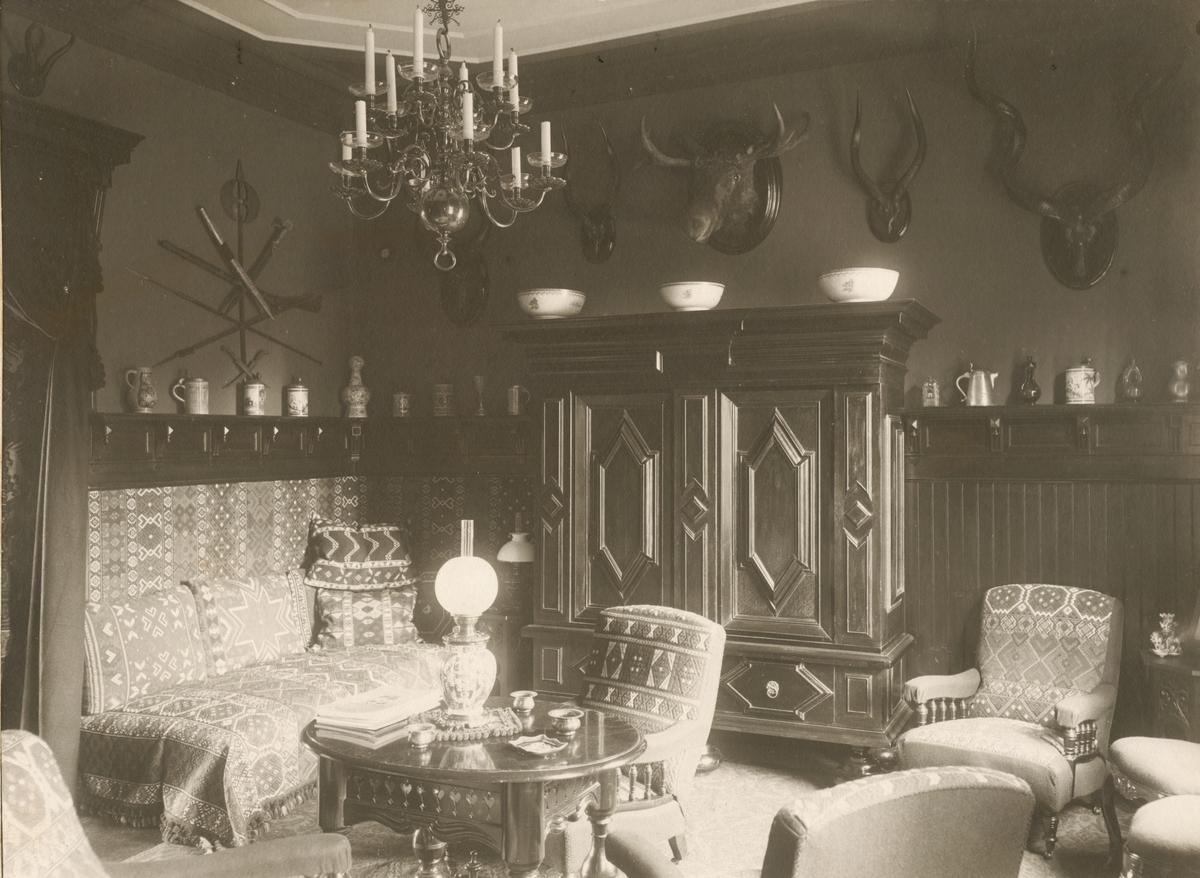 Interiör från Villa Rettig, Gävle. Rummet inrett i orientalisk stil med divan. På väggen jakttroféer.