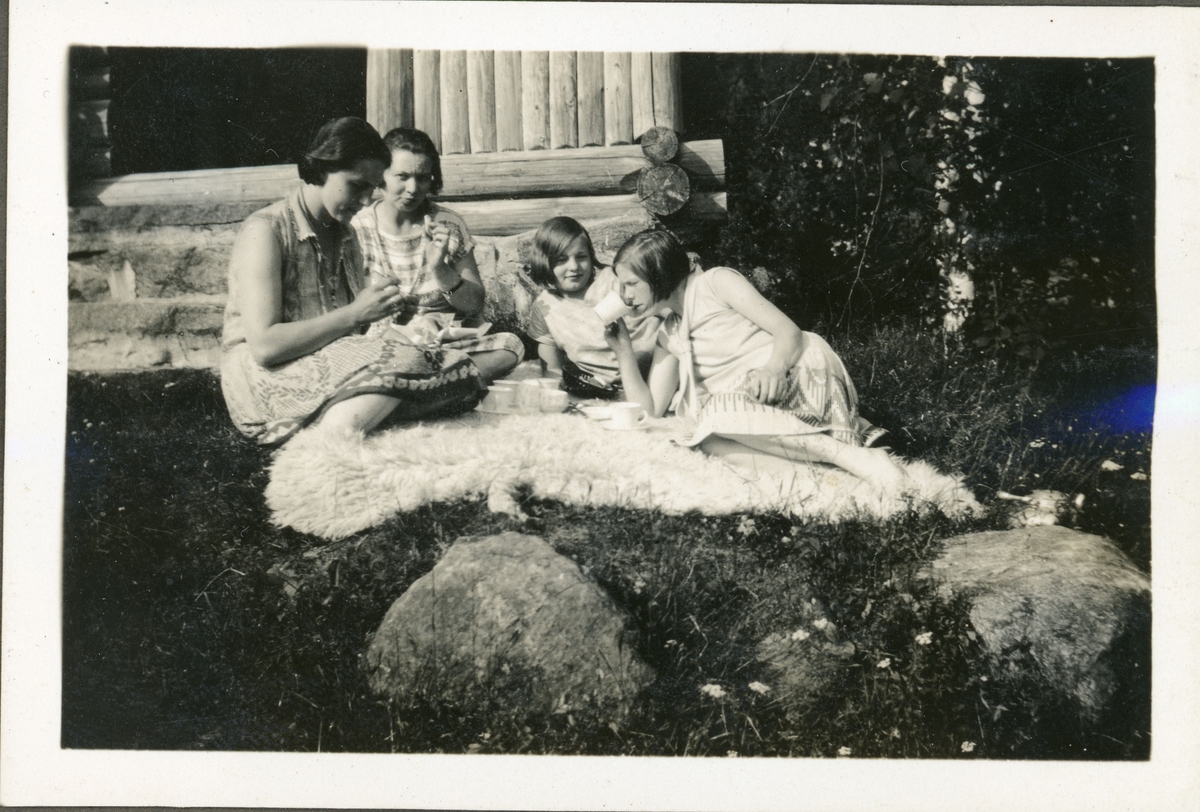 Fire jenter har piknik foran hytta. Ingelsrudsjøen. Trolig 1930-tall.