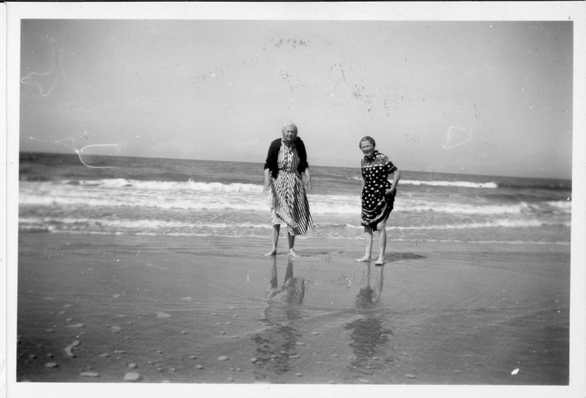 To kvinner vasser på strand, trolig etter andre verdenskrig.