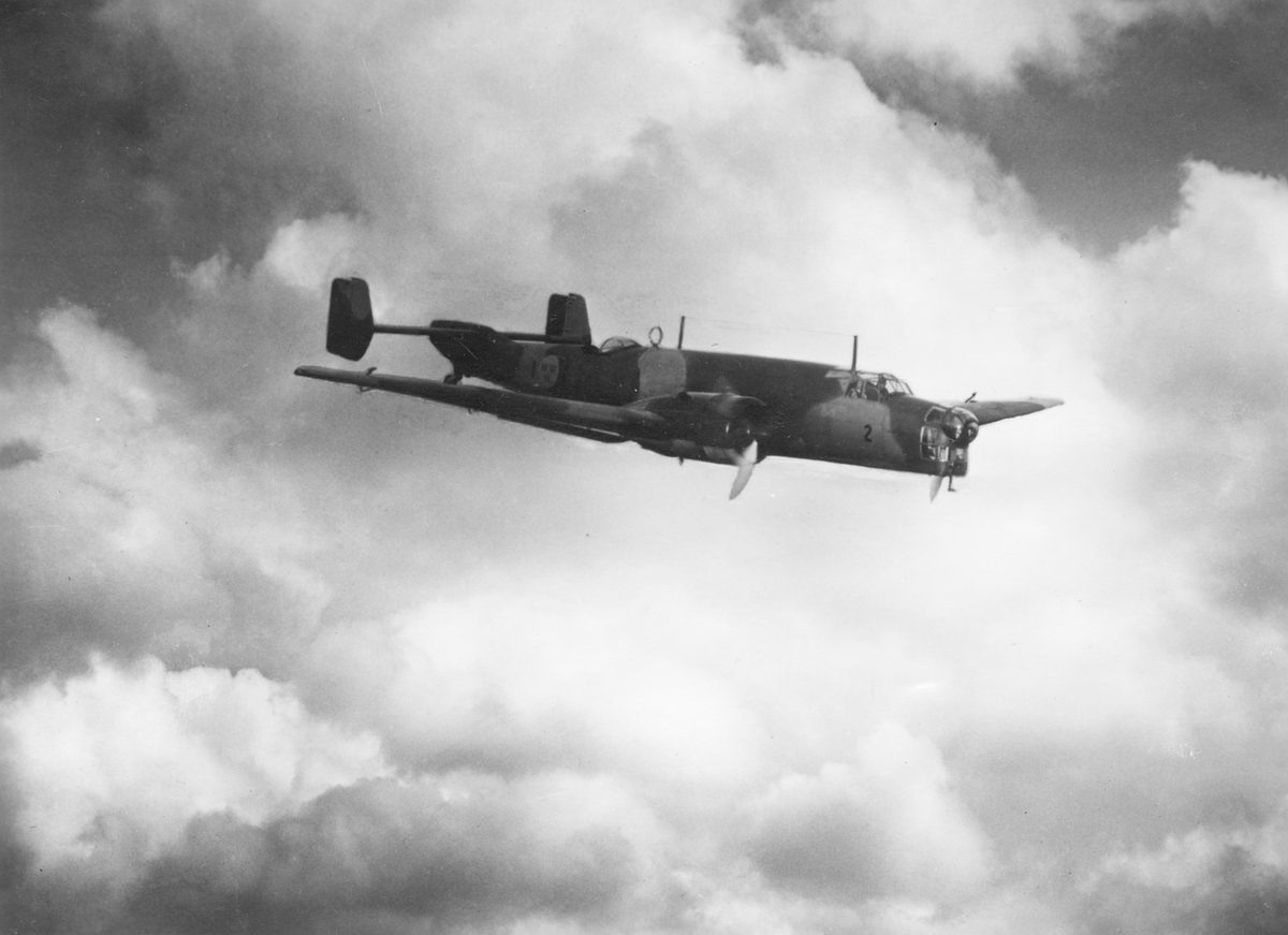 Flygbild av flygplan B 3 Junkers Ju 86K i luften. Märkt F 1-2, från Västmanlands flygflottilj. Molnig himmel i bakgrunden.