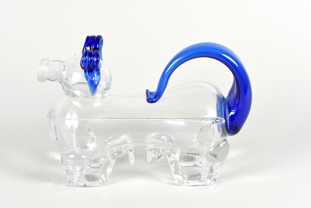 Brännvinsflaska i form av en hund, så kallad fyllehund. Tillverkad i klart och blått glas, svans och öron är blåa. Svansen fungerar som handtag.