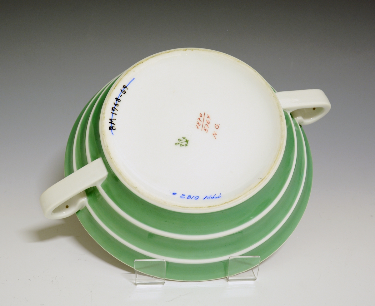 Lokkefat av porselen. Samme form og størrelse som  BM. 1968:60. Malt i lys grønn farge med utsparinger i hvitt for hanken, kanten m.v.
Modellnr. 1870
Dekornr: 5764