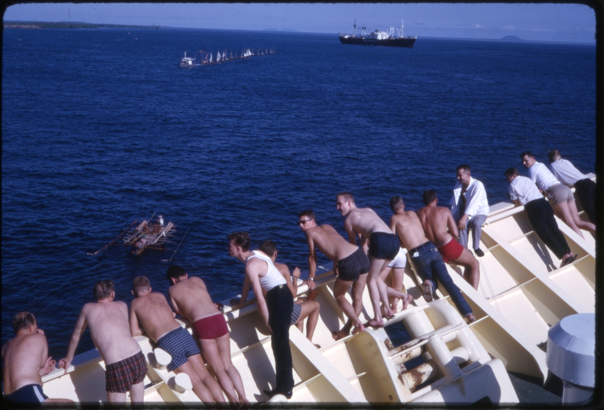 Turister ser på fiskere i fiskebåter, fra baugen på cruiseskipet 'M/S Sagafjord', med ukjent skip i bakgrunnen. 'Sagafjord' Around The World via Africa Cruise 1966.