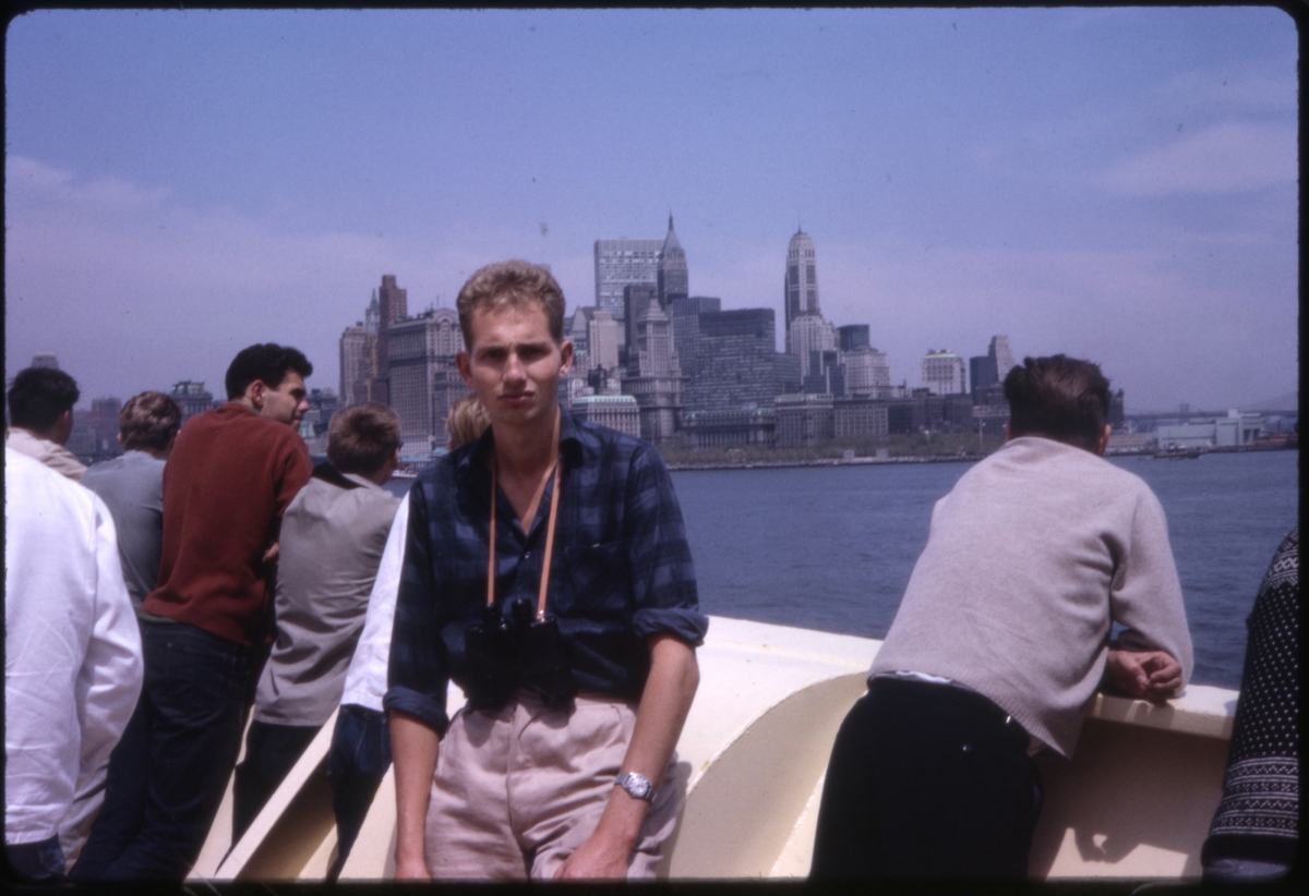 Mann, med flere mennesker rundt, om bord på cruiseskipet 'M/S Sagafjord', med utsikt over nedre Manhattan, New York, U.S.A. 'Sagafjord' Spring Cruise to Europe 1966.