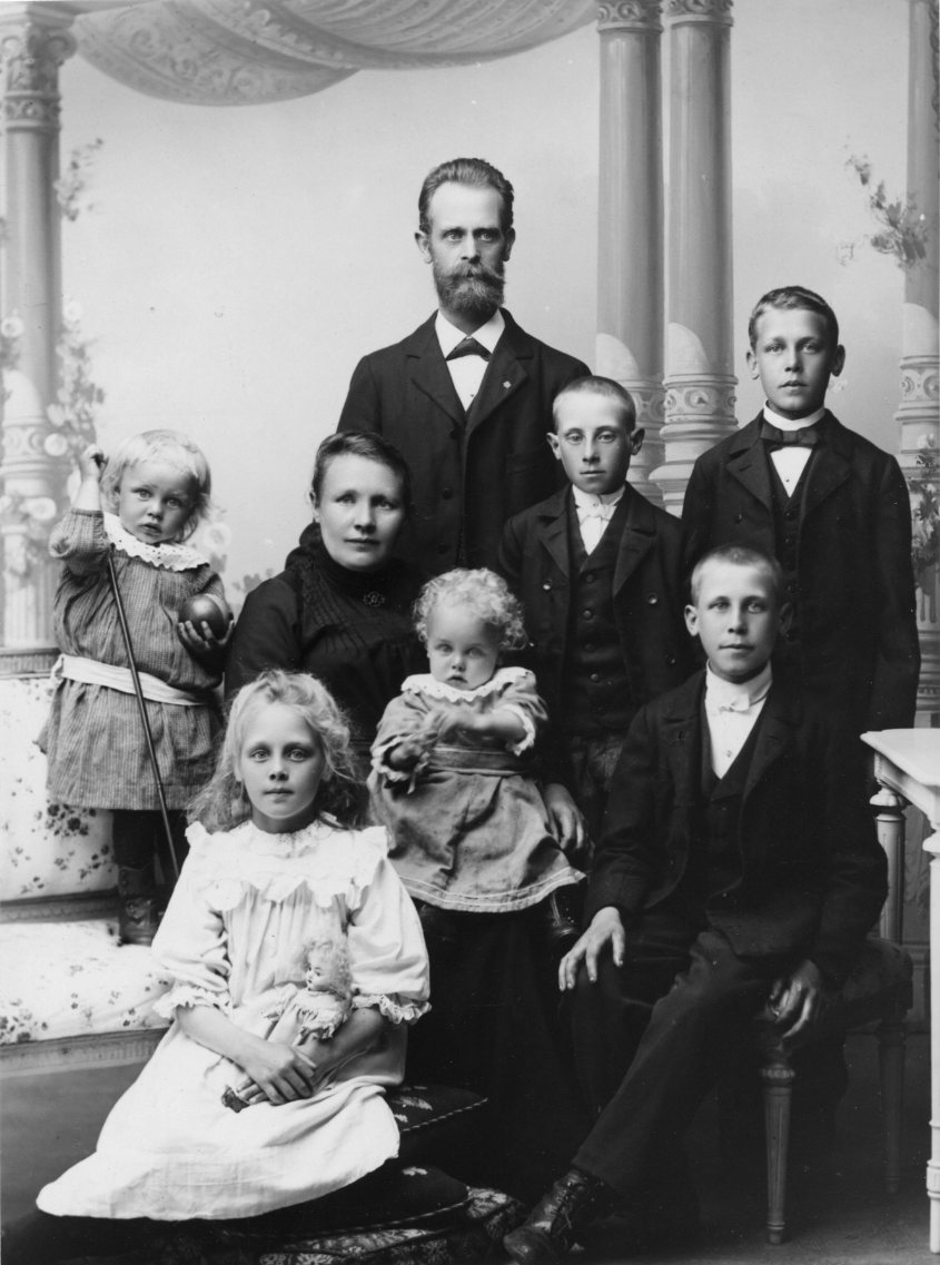 Gruppbild med familjen Johan Alfred Johansson, stående. Hustrun Johanna Johansdotter sitter på en stol framför mannen med ett litet barn i knät. Pojken som sitter på en stol till höger heter Hugo