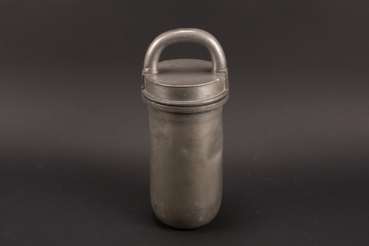 Cylindrisk glassform av tenn. Lock med halvcirkelformat handtag. Formens botten är något rundad.