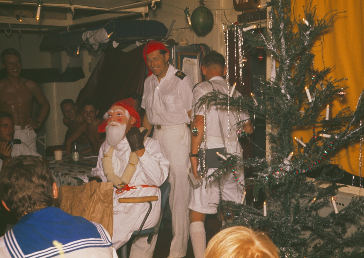 Bilden visar utdelning av julklappar ombord på Älvsnabben. Två besättningsmedlemmar är utklädd som jultomtar, även julgranen saknas inte.