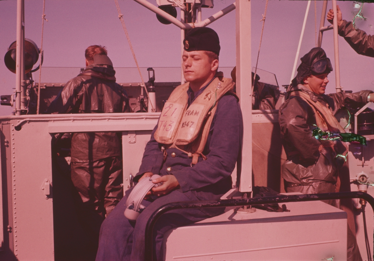Bilden visar en sjöman med skyddskläder och flytväst som vilar i solsken ombord på T 43.
