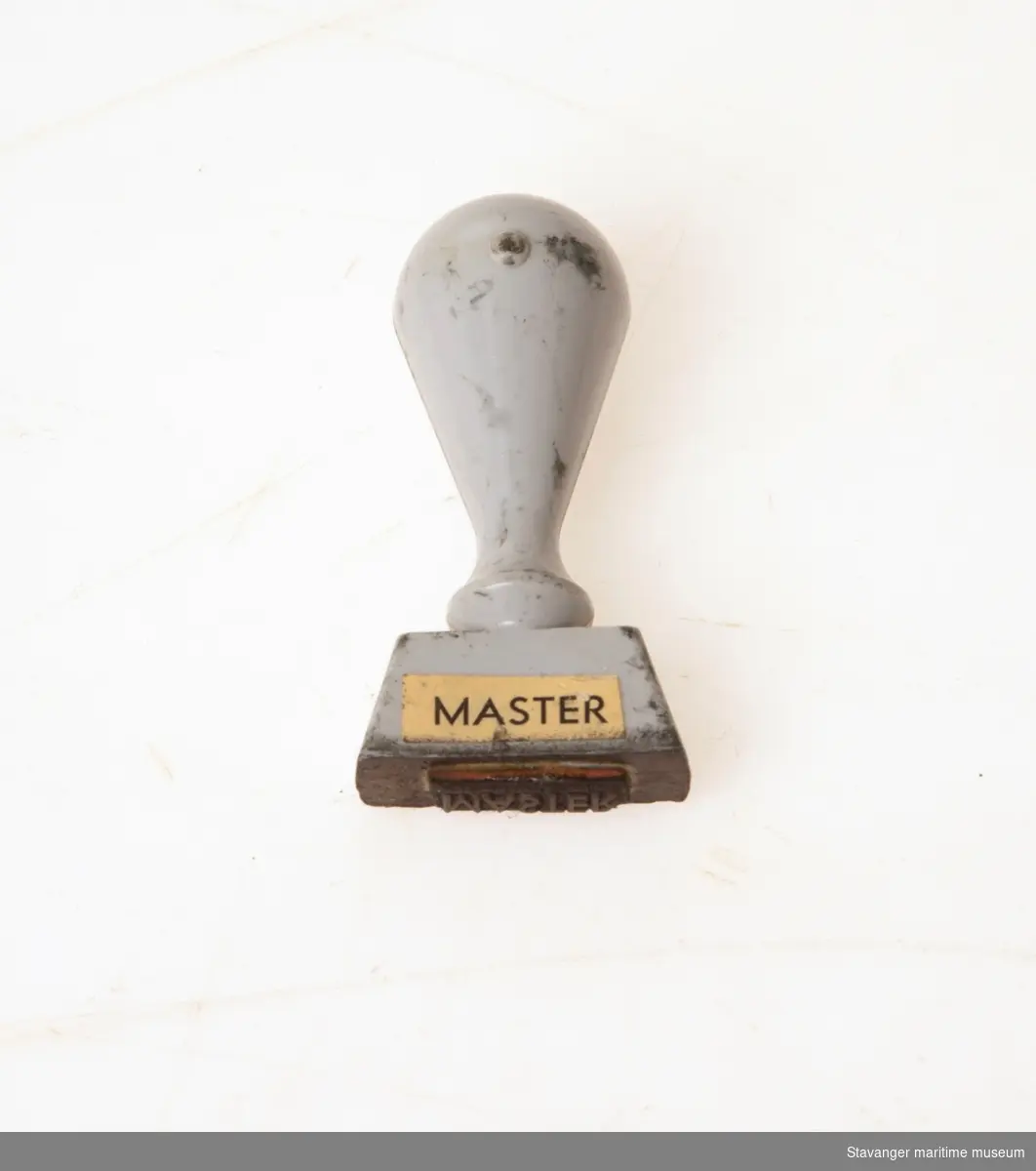 Stempel i tre og malt grå, hvor det står: Master.