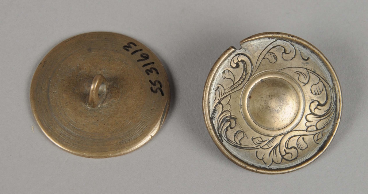 Støpt og gravert knapp av bronse. Knappen har gravert akantusdekor i en ring rundt et opphøyd midtparti. På den ene knappen er det inngravert et ansikt på midtpartiet. Den ene knappen har et hakk i kanten.