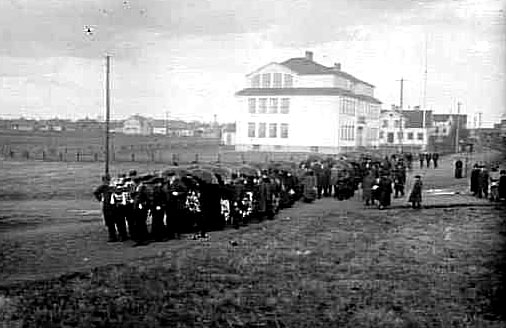 Stationskarl Erikssons begravningsprocession med standar i teten passerar Töreboda skola 1926.