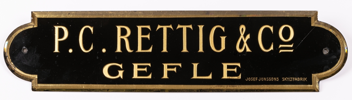 Namnskyltar, 4 stycken, i glas, svartmålad med guldfärgad text.
"P.C. Rettig & Co Gefle".