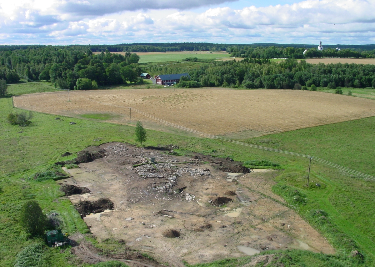 Översiktsbild av gravfältet RAÄ Rogberga 19, L1973:5423 i Bogla i Rogberga socken, Jönköpings kommun, medan det genomfördes en arkeologisk undersökning av gravfältet år 2003. I bakgrunden syns Bogla skattegård och Rogberga kyrka.