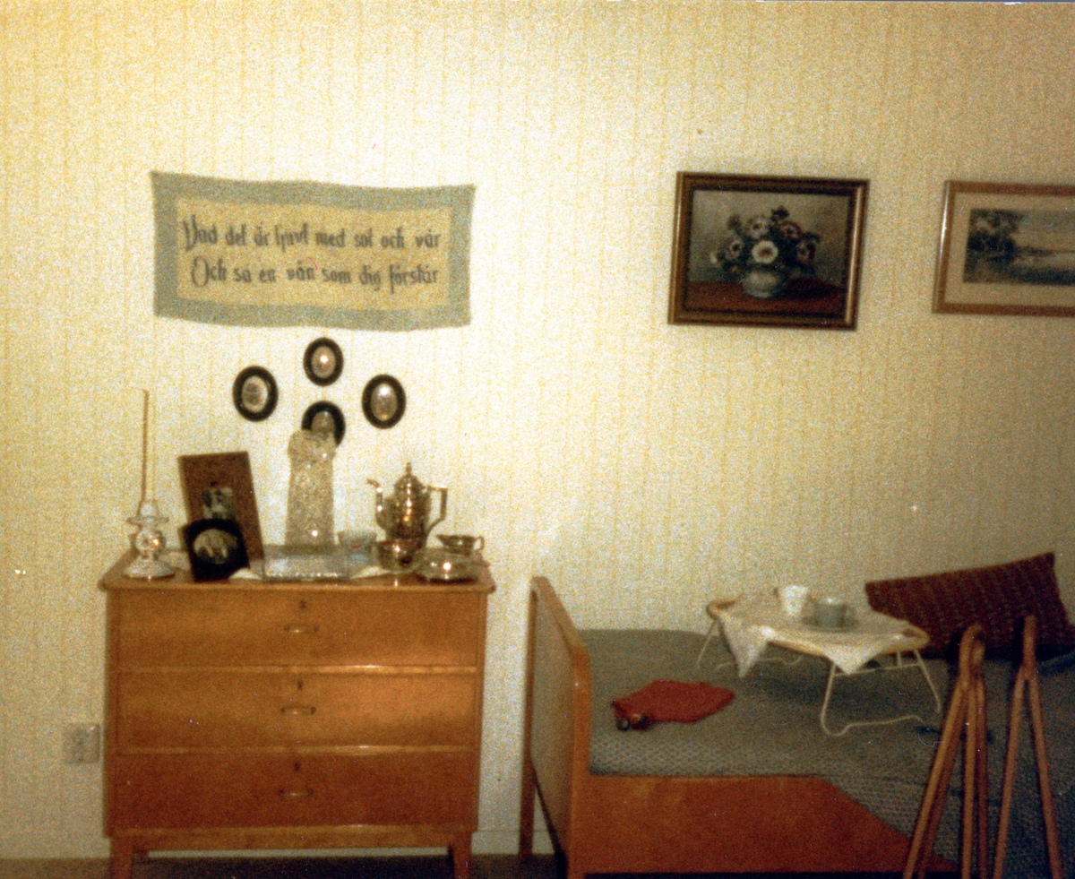 Brattåsgården vid invigningen år 1986. Utställning av föremål från gamla Brattåshemmet, gjord av Kållereds Hembygdsgille. Delar av föremålen finns nu på Mölndals stadsmuseum. Här ses en byrå, del av säng, väggbonad och tavlor.