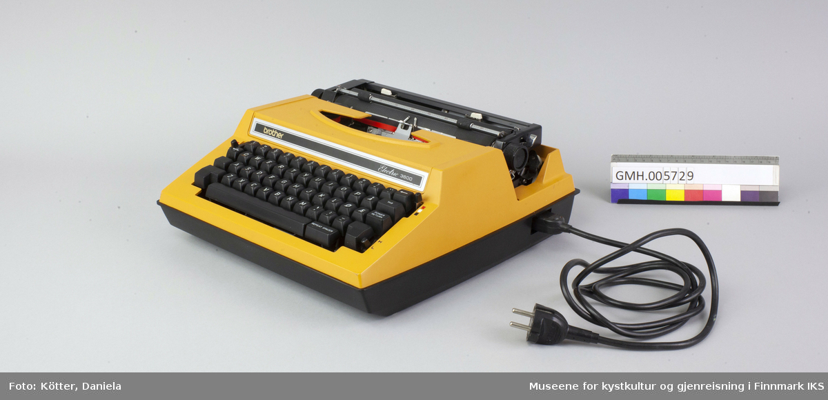 Dette er en elektrisk skrivemaskin med en korpus av oransje og svart kunststoff. Maskinen fungerer. Den kan brukes for papir opp til A4-format og brukes med tofarget bånd, slik at bokstavene kan skrives i svart eller rødt. Til transport, kan det settes det på et lokk av svart kunststoff.     